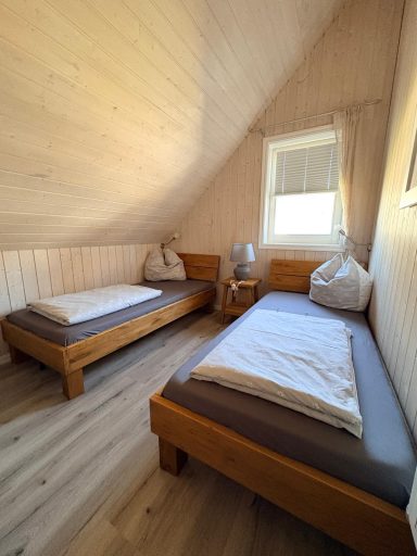 Helles Dachzimmer mit zwei Einzelbetten und einem Nachttisch.