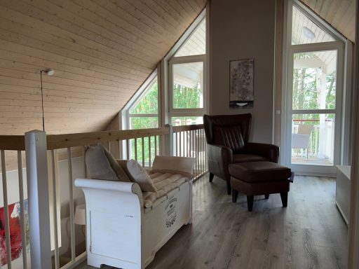 Gemütlicher Raum mit Holzdetails, einem Sessel und einer Sitzbank unter einem Dachfenster.