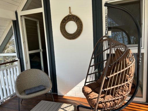 Sitzecke auf einem Balkon mit einem hängenden Stuhl und einem runden Spiegel.