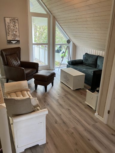 Wohnzimmer mit einem Sessel, einer Couch, einem Tisch und hellen Wänden.