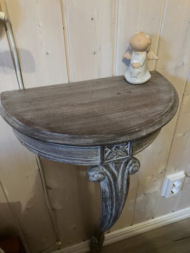 Halbmondtisch aus Holz mit einer kleinen Figur darauf, vor einer hellen Wand.