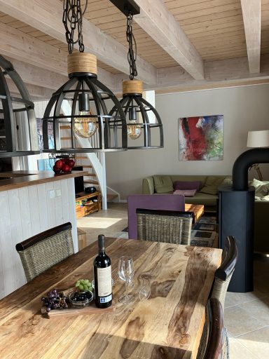 Modern Wohnzimmer mit Holzstühlen, Weinfläsche, und eleganten Leuchten.