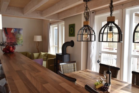 Helle Wohnküche mit Holzbar, Pendelleuchten und gemütlicher Sitzecke.