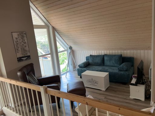 Gemütliches Wohnzimmer mit blauer Couch, Sessel und hellem Holzboden.