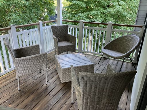 Gemütliche Terrasse mit vier Stühlen und einem quadratischen Tisch aus Rattan.