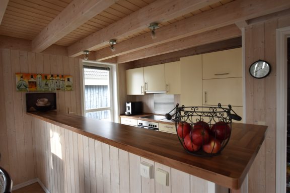 Helle Küche mit Holzdekor, Obstschale mit Äpfeln auf der Theke.