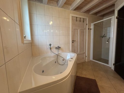 Badewanne in einem hellen Badezimmer mit Dusche und Holzdecke.