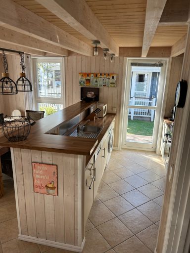 Moderne Küche mit Holzregalen, Schränken und Blick auf den Außenbereich.