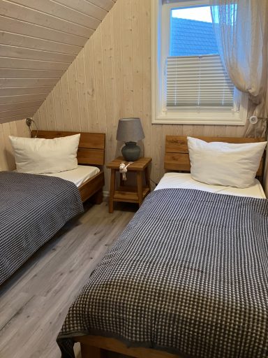 Zwei Einzelbetten in einem hellen, gemütlichen Schlafzimmer mit Holzdetails.