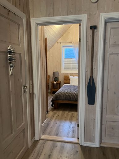 Ein Blick durch einen Türrahmen auf ein Schlafzimmer mit Bett und Fenster.