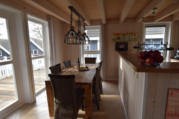 Heller Essbereich mit Holztisch, Stühlen und großen Fenstern.