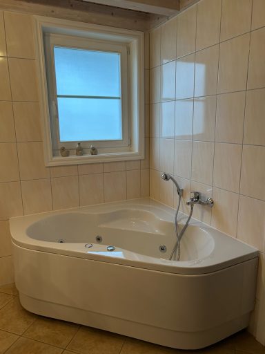 Eckbadewanne mit Whirlpool-Funktionen und Fenster in einem Bad.