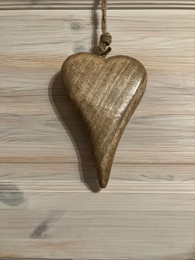Herzförmiger Anhänger aus Holz, hängend an einem Schnürsenkel.