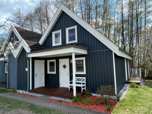 Dunkelblaue, zweigeschossige Ferienwohnung mit weißen Fenstern und Eingangsbereich.