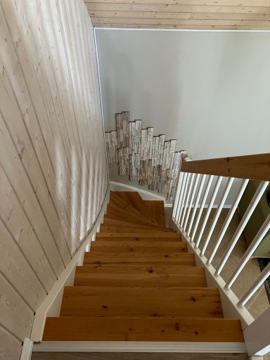 Holztreppe mit gelblichen Stufen und weißen Wänden, Blick von oben.