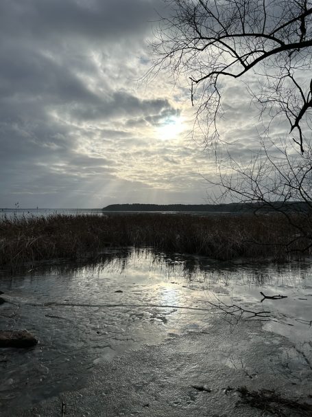 Dämmerung über einem ruhigen Gewässer mit reflektierendem Licht und bewölktem Himmel.