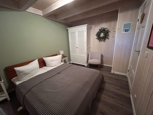 Gemütliches Schlafzimmer mit Doppelbett, Holzfußboden und Wandschmuck.