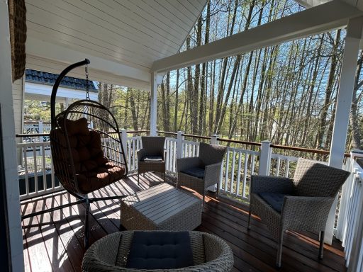 Entspannter Balkon mit Hängestuhl und Sitzgelegenheiten, umgeben von Bäumen.